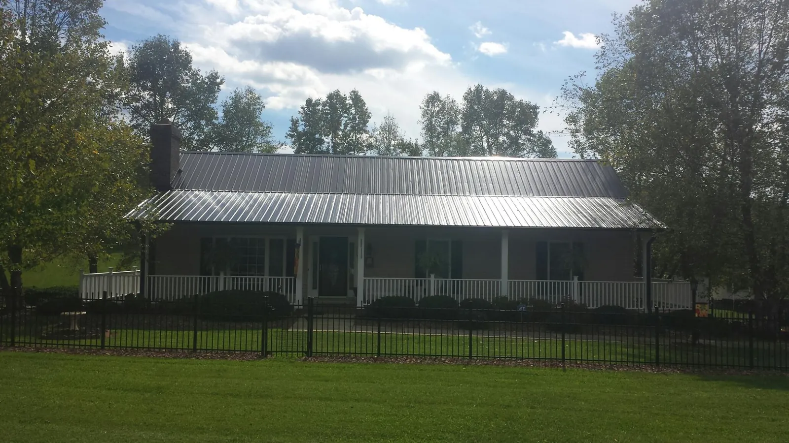 Gray metal roof on a brick ranch with a full width front porch — Gutter Guard Installation work by our crew in Genoa